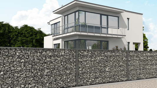 Gabionenzaun aus Metall und Steinen als robuste Zaunanlage vor modernem Haus – MY-Zaunsysteme