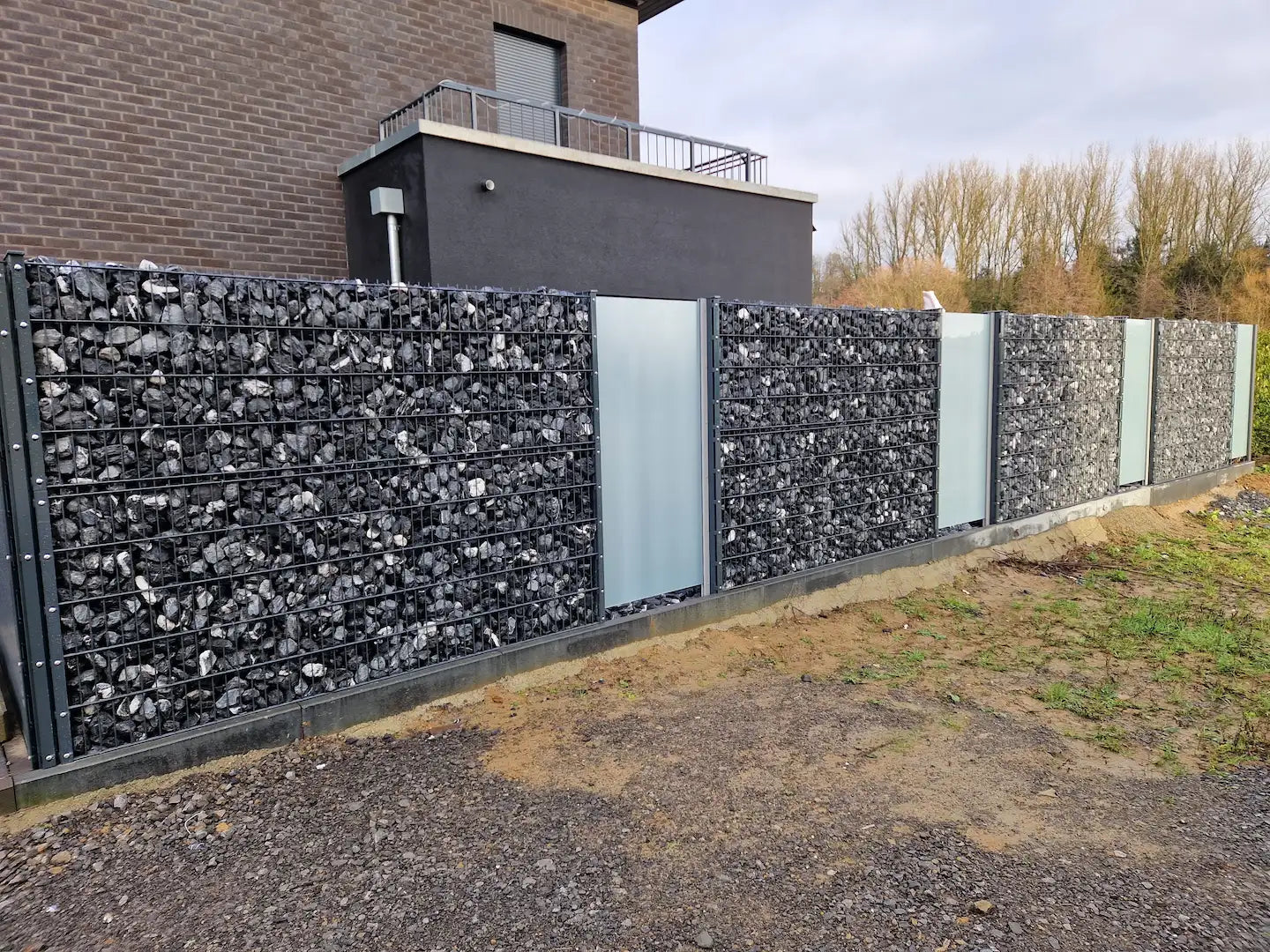 Gabione mit Glas, Metall und Steinen als Zaunanlage vor modernem Haus – MY-Zaunsysteme